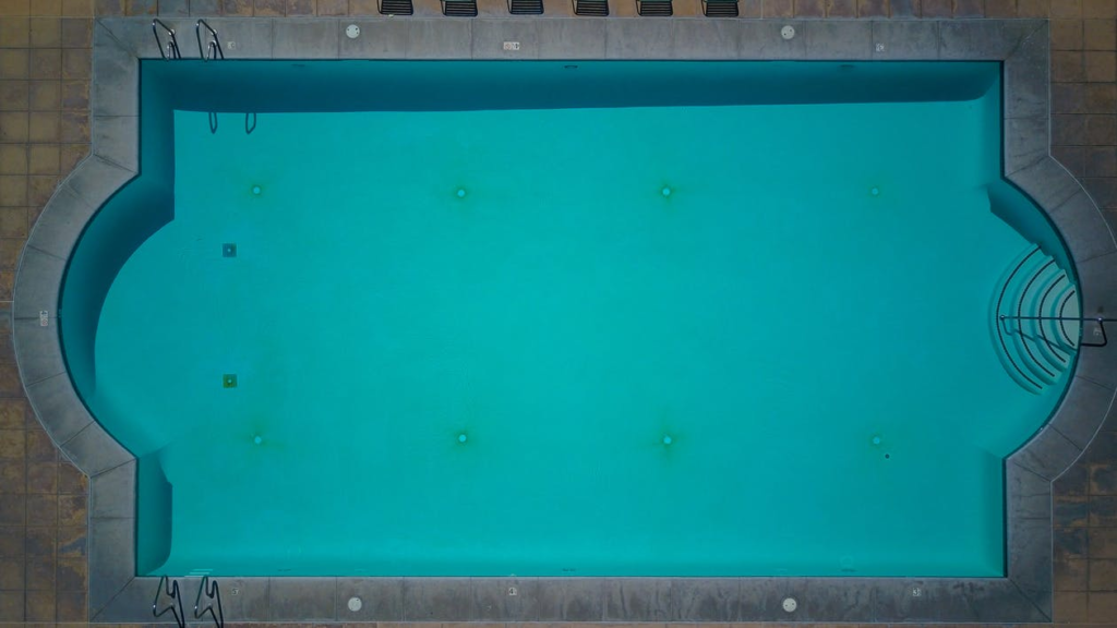 A dirty swimming pool with a stained deck