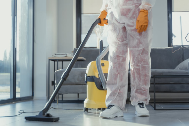 A professional cleaner in PPE vacuuming a floor